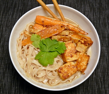 Vegane Reisbandnudelsuppe mit würziger Brühe, Sriracha-mariniertem Tofu und geröstetem Sesam-Wurzelgemüse
